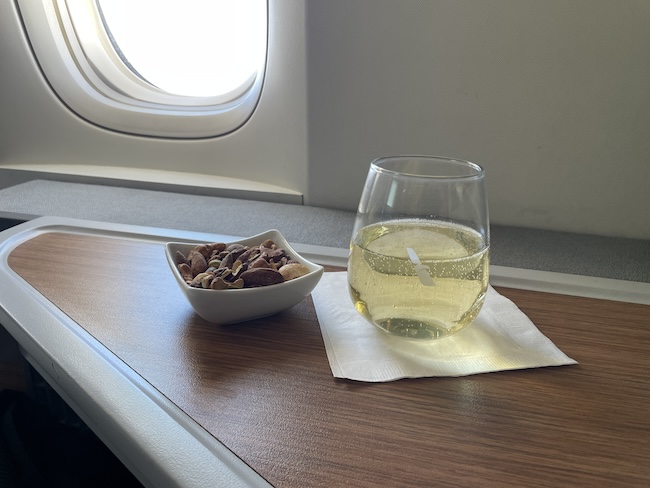 a glass of wine and a bowl of nuts on a table