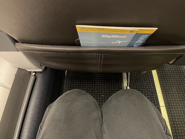 a person's legs and a book in a seat