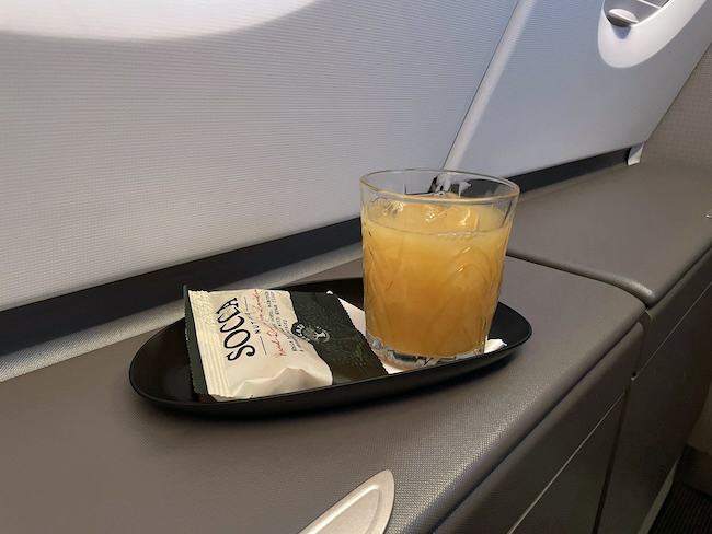 a glass of orange juice and a packet of food on a tray