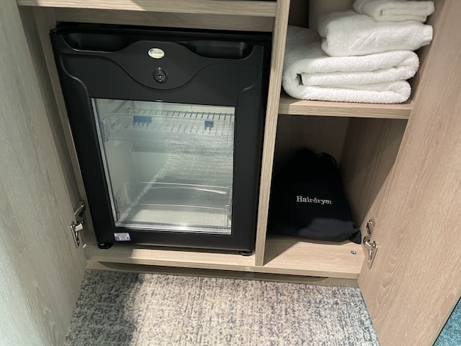 a small refrigerator with a towel on the shelf