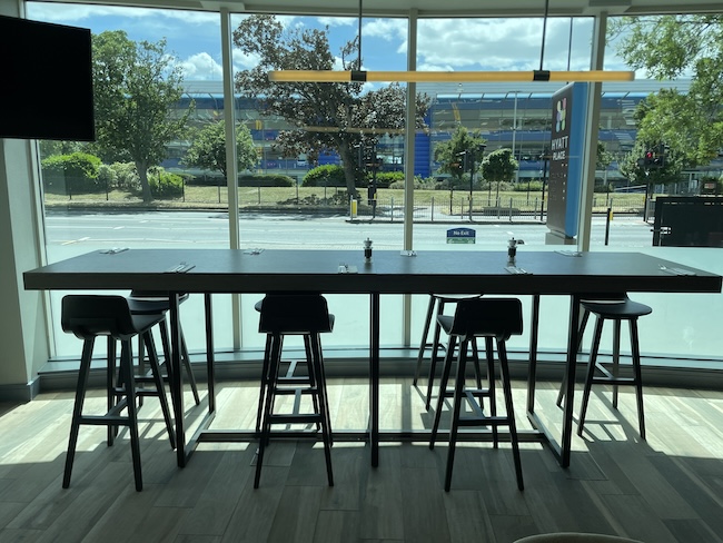 a long table with stools in a room with a window