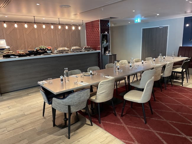 a long table with chairs and a red rug