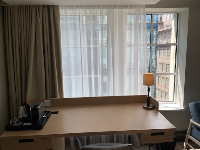 a desk in a room with a window and curtains