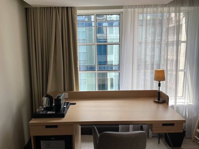 a desk with a lamp and a chair in a room with curtains