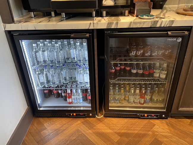 a two refrigerators with bottles of soda and a glass door