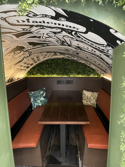 a table with orange seats and pillows in a green archway