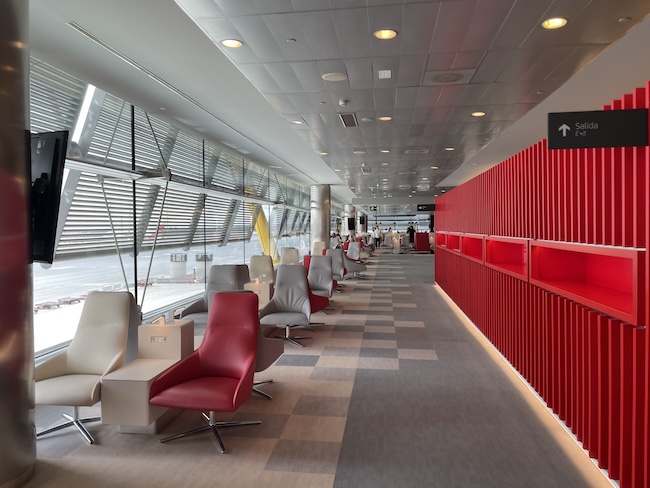 a long room with chairs and a red wall