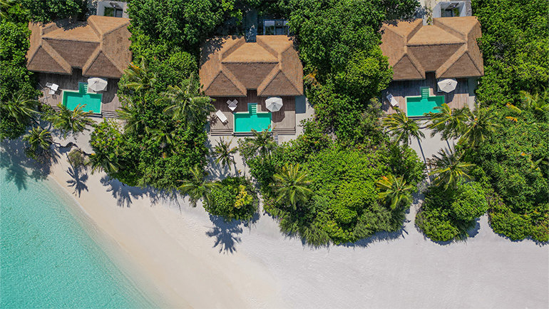 a house with a pool and trees on a beach