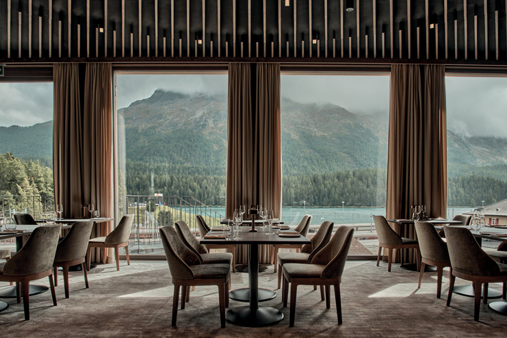 a room with tables and chairs and a view of mountains and trees