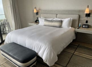 a bed with a white bedding and a black and white bench