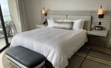 a bed with a white bedding and a black and white bench