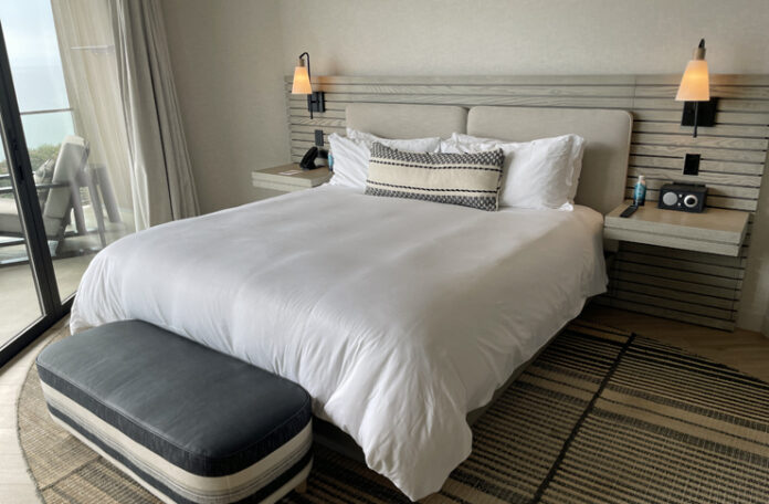 a bed with a white bedding and a black and white bench