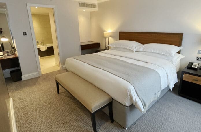 a bed with a bench and lamps in a room