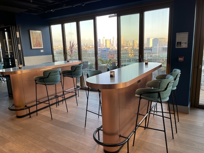 a bar with chairs and a table in a room with a view of a city