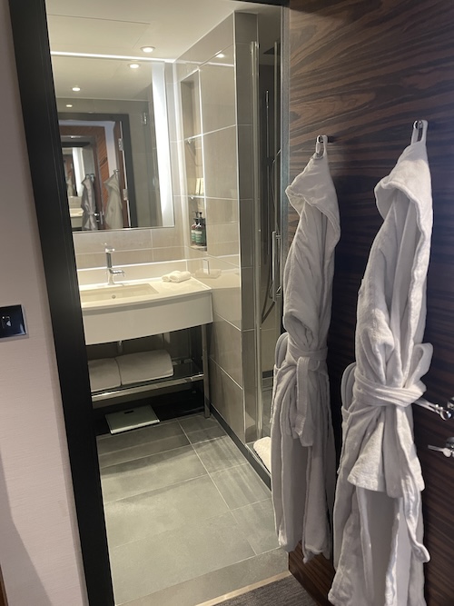 a bathroom with white bathrobes and a sink