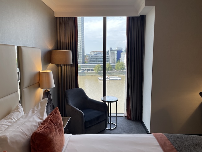 a room with a bed and a window with a river and city view