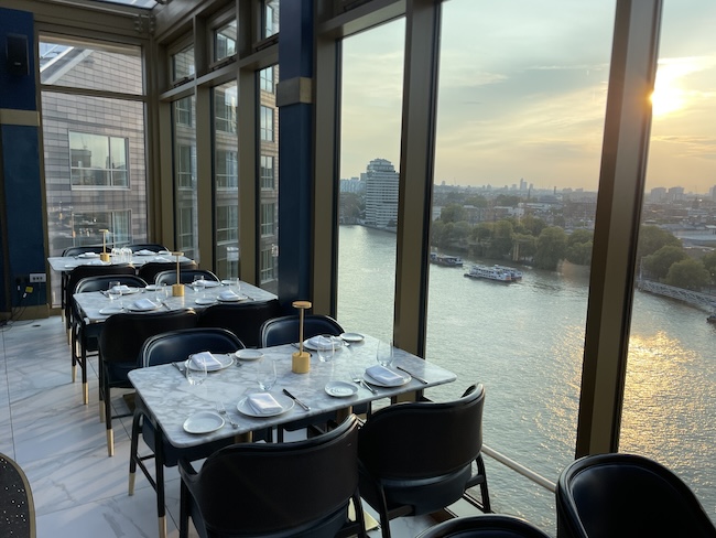 a room with tables and chairs and a view of a river