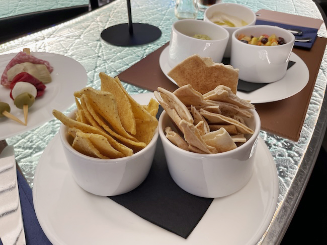 a group of bowls of chips and dips on a table