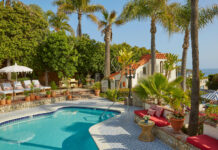 a swimming pool with palm trees and a house