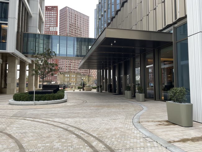 a walkway with glass walls and a walkway leading to a building