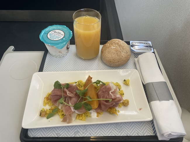 a plate of food and a glass of juice on a tray