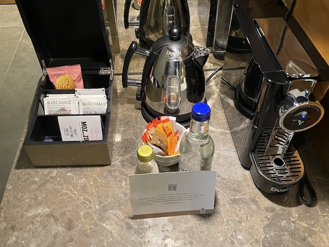 a coffee machine and a small container with a card and a bottle of liquid