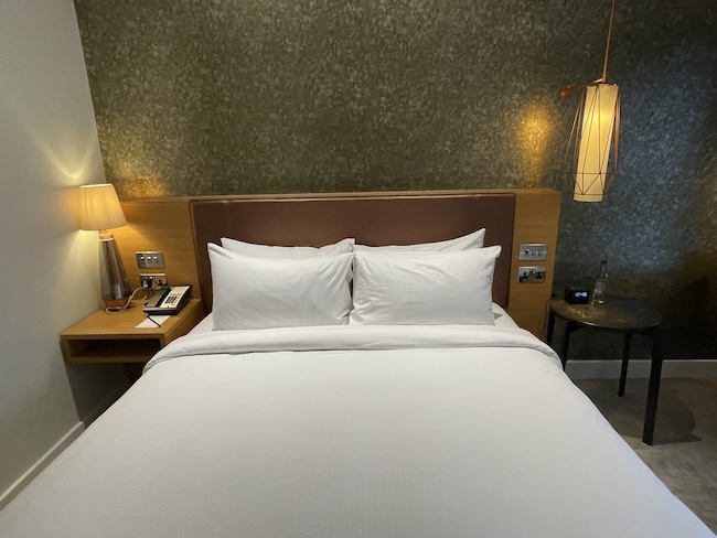 a bed with white sheets and lamps
