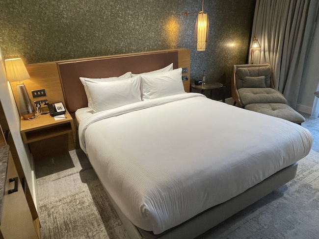 a bed with white sheets and a chair in a room