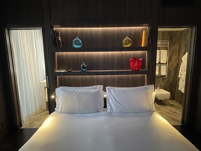 a bed with white pillows and a shelf with lights
