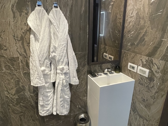 a bathroom with white bathrobes and a sink
