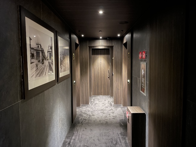 a hallway with two doors and pictures on the wall