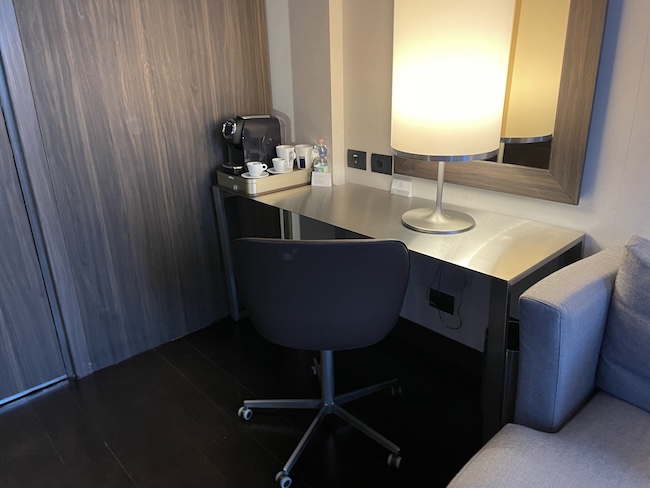a desk with a lamp and coffee cups on it