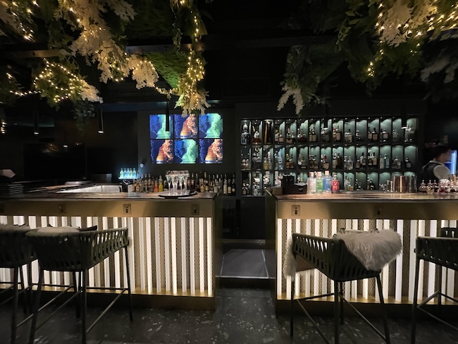 a bar with shelves of liquor and lights