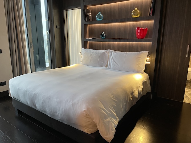 a bed with white sheets and a shelf with lights