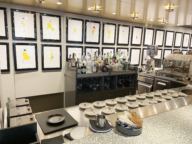 a room with a long counter with plates and bottles on it
