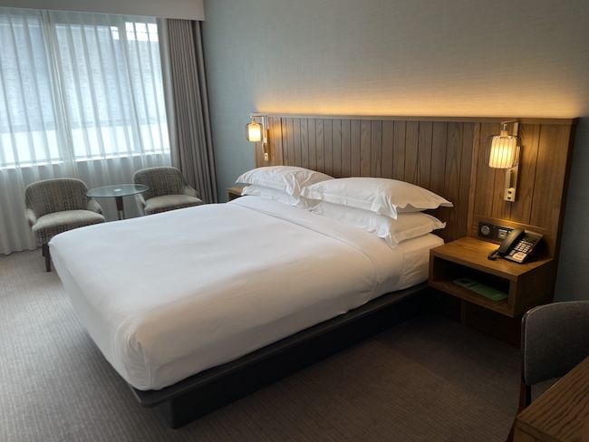 a bed with white sheets and a wood headboard in a hotel room