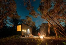 people sitting on a bench in front of a small house