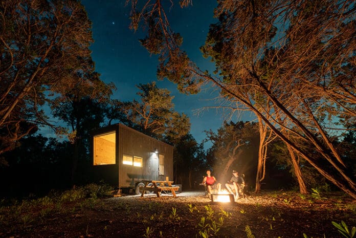 people sitting on a bench in front of a small house