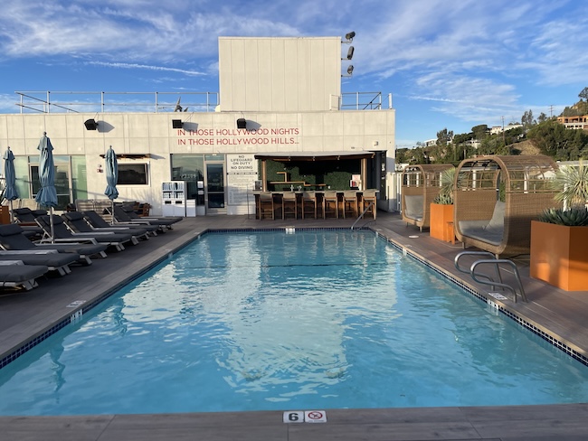 a pool with chairs and a building in the background
