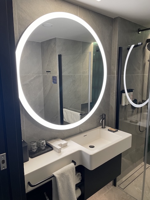 a bathroom with a round mirror and a sink
