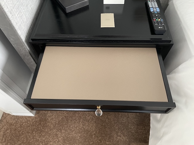 a black nightstand with a remote control and a book on it