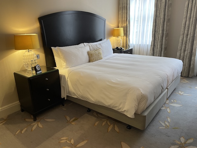 a bed with a black headboard and a lamp next to it