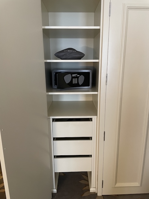a small white cabinet with a black microwave on top
