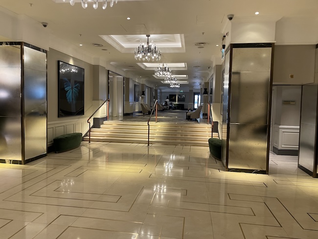 a hallway with stairs and chandeliers