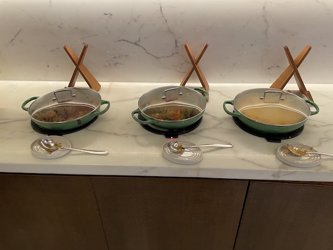 a row of pots with spoons on a counter