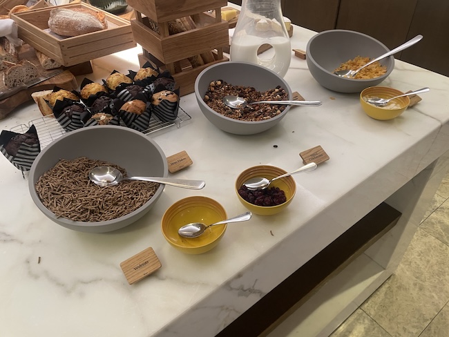 a table with bowls of cereal and muffins