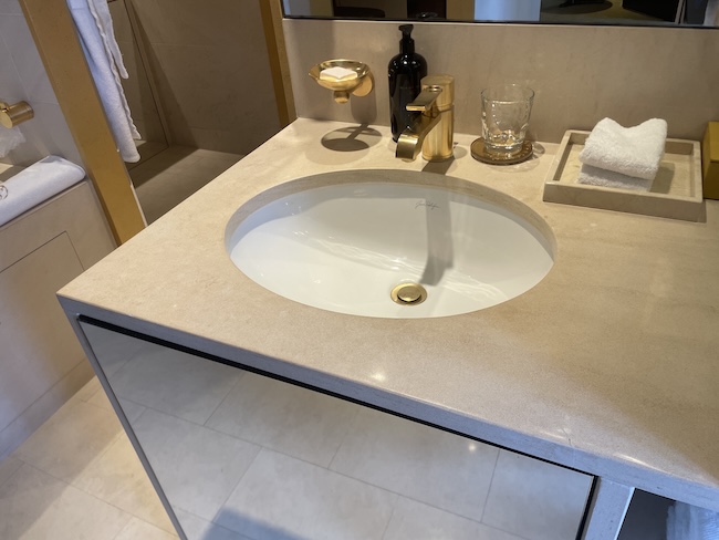 a sink with a gold faucet and a glass on the counter