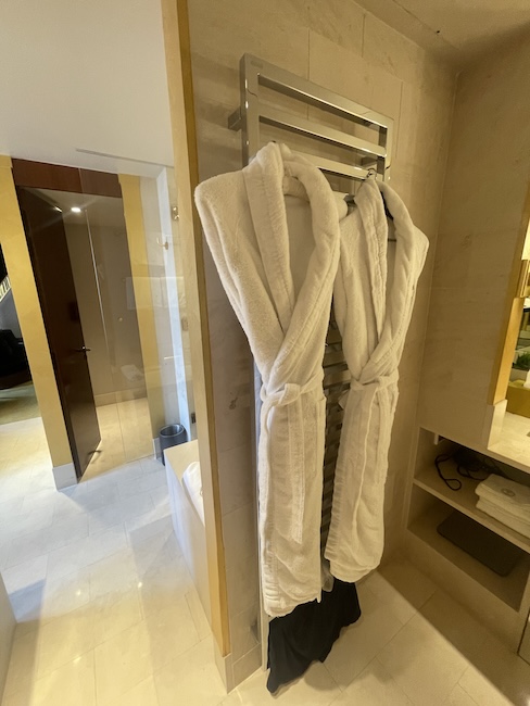 a white bathrobes on a towel rack