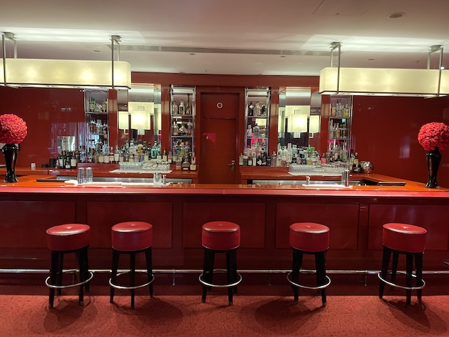 a bar with red stools and lights