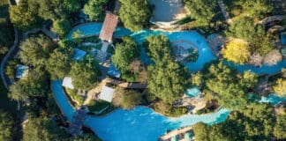 an aerial view of a pool surrounded by trees